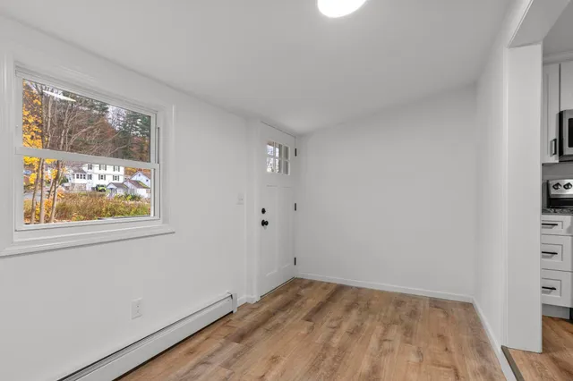 a view of an empty room with wooden floor and a window