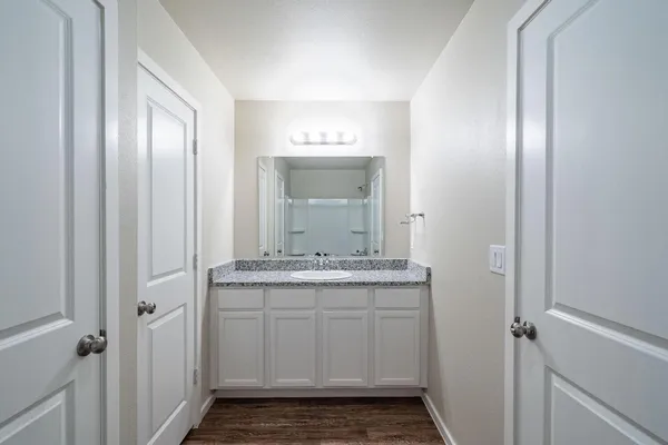 a bathroom with a granite countertop sink a mirror and a shower