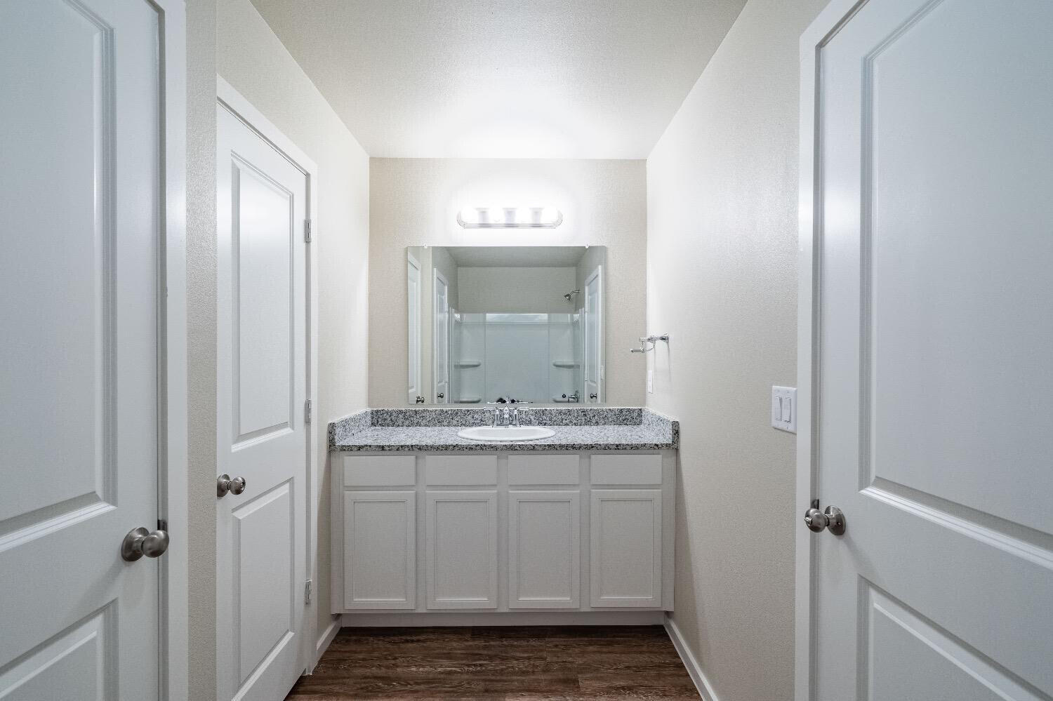 9706 Saratoga Avenue Lubbock, TX 79424 - Photo 7 of 11 a bathroom with a granite countertop sink a mirror and a shower