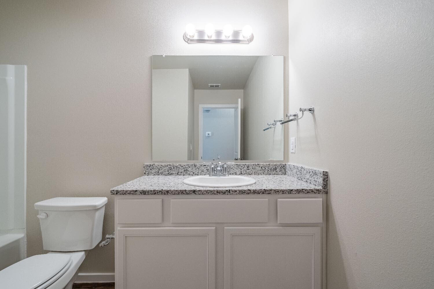 9706 Saratoga Avenue Lubbock, TX 79424 - Photo 9 of 11 a bathroom with a granite countertop toilet sink and mirror