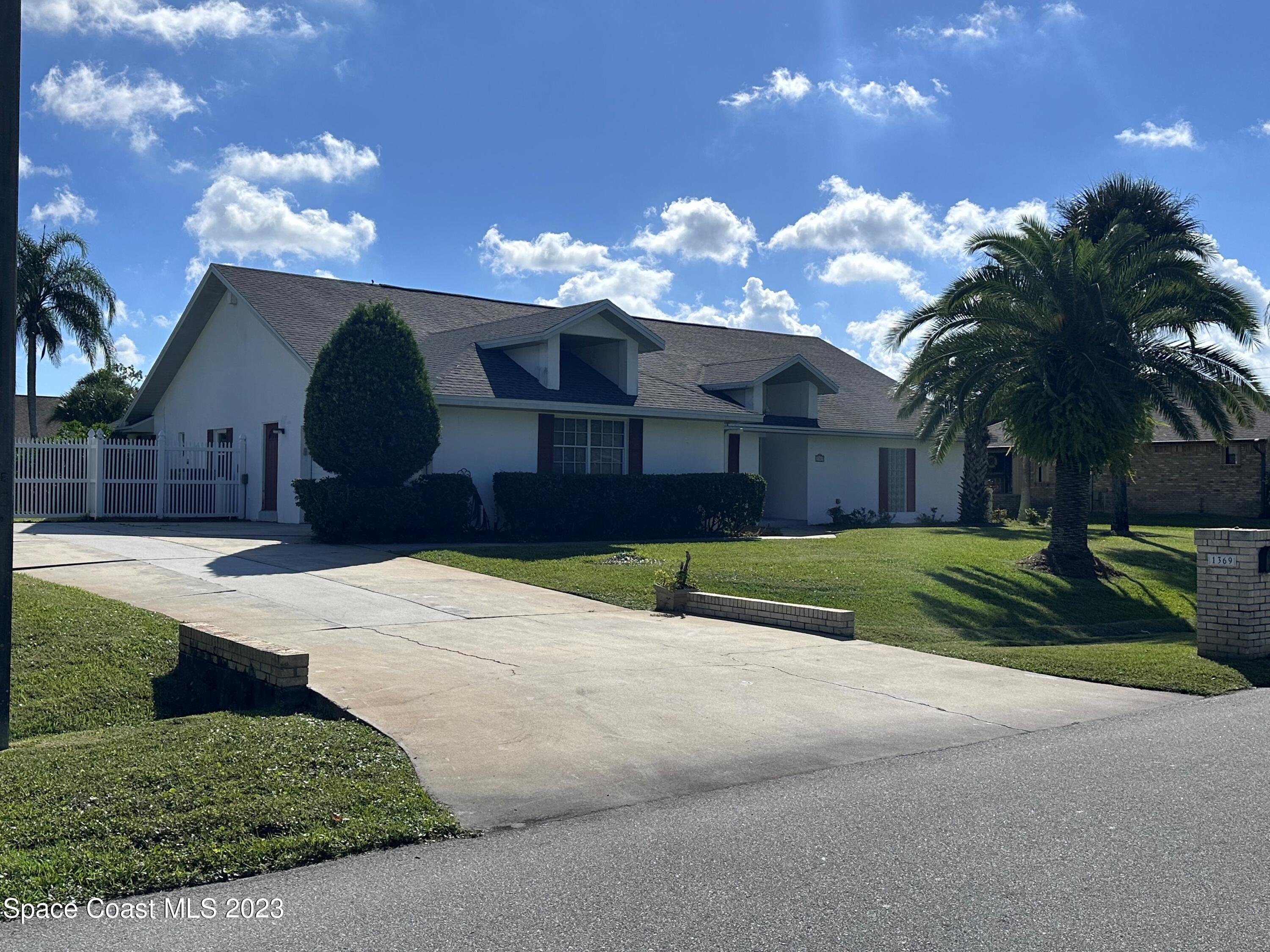 a view of a house next to a yard with palm trees
