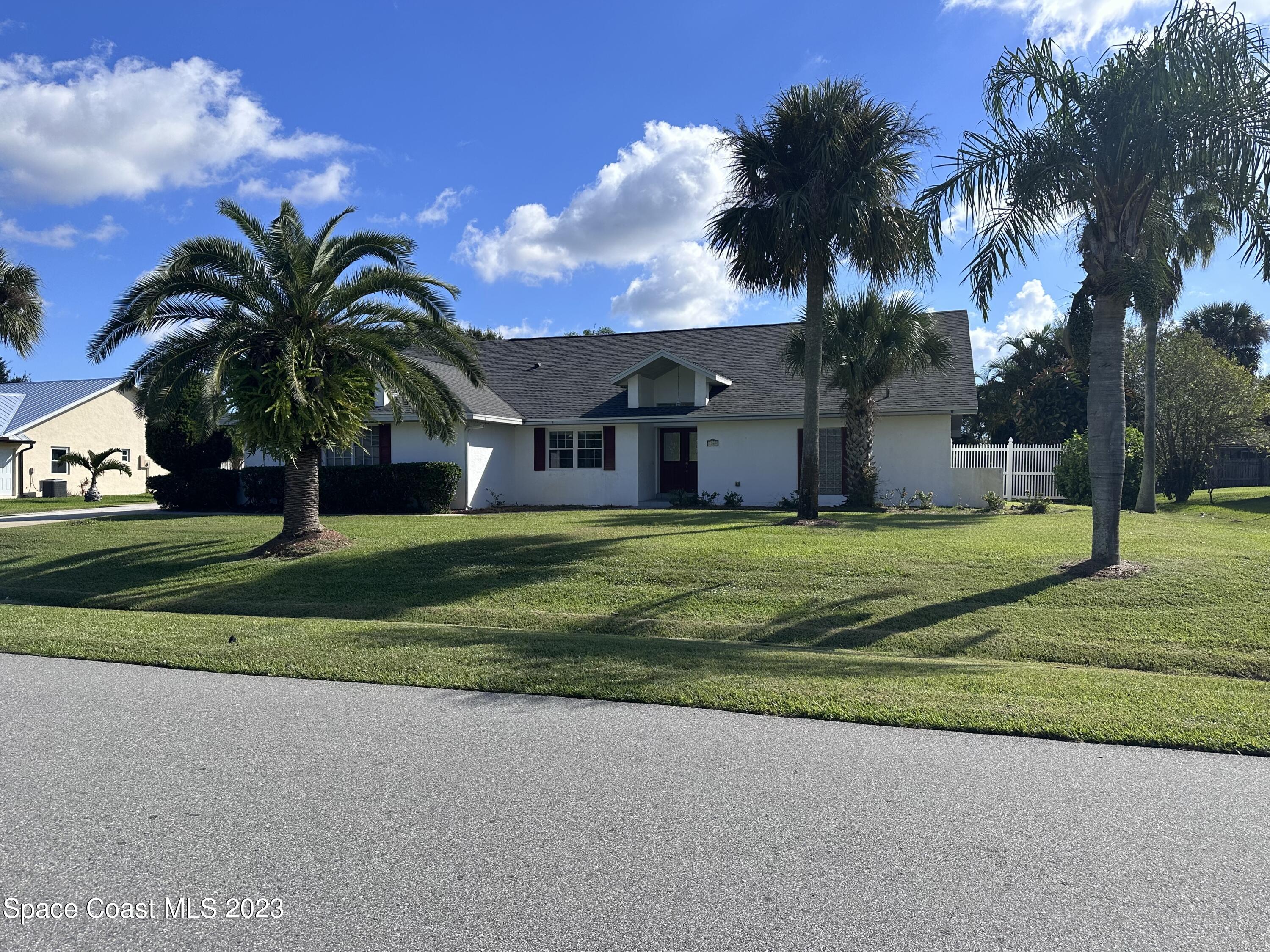 1369 Elcon Drive Melbourne, FL 32904 - Photo 11 of 13 a view of a house with a big yard and palm trees