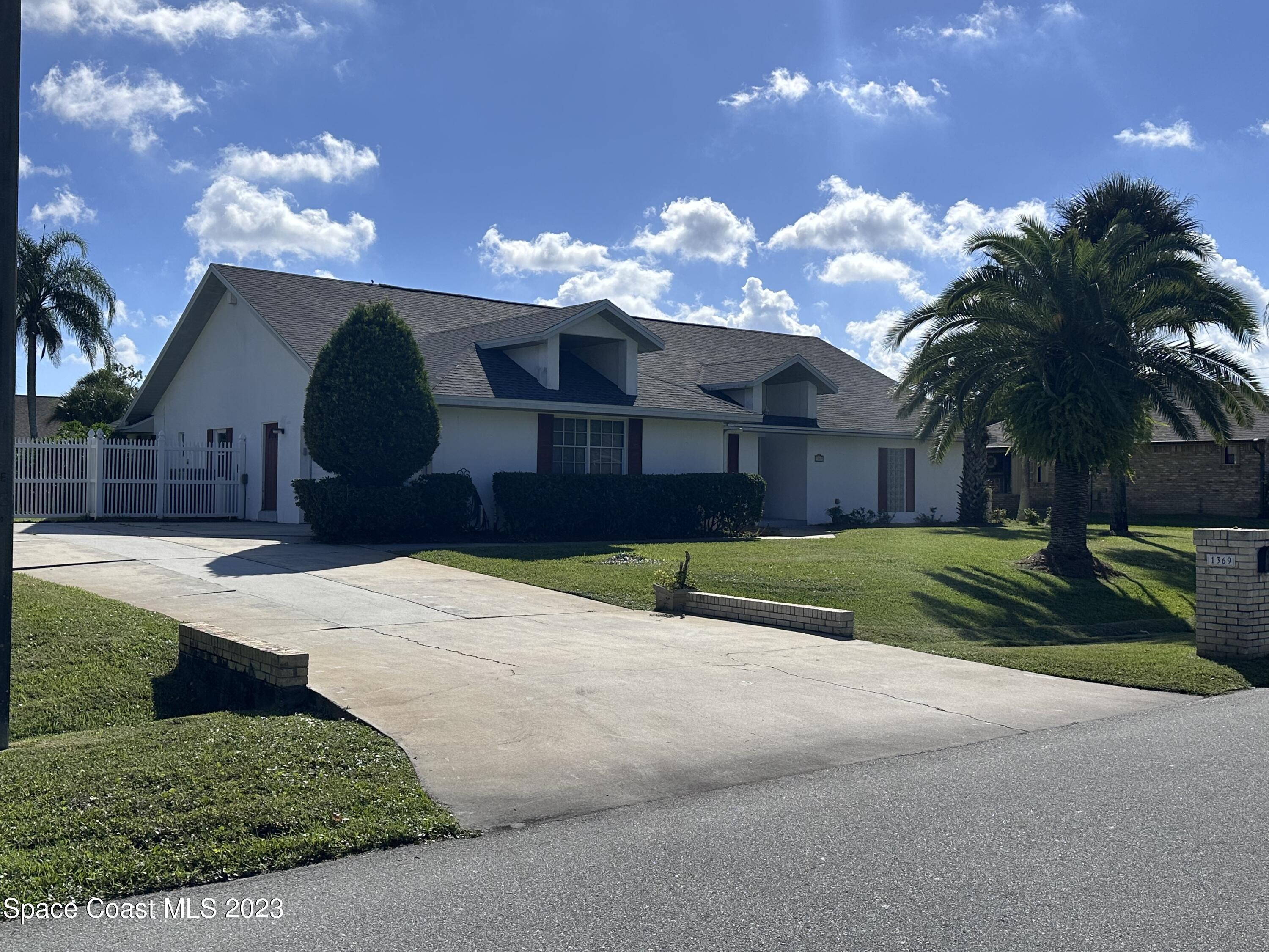1369 Elcon Drive Melbourne, FL 32904 - Photo 13 of 13 a view of a house next to a yard with palm trees