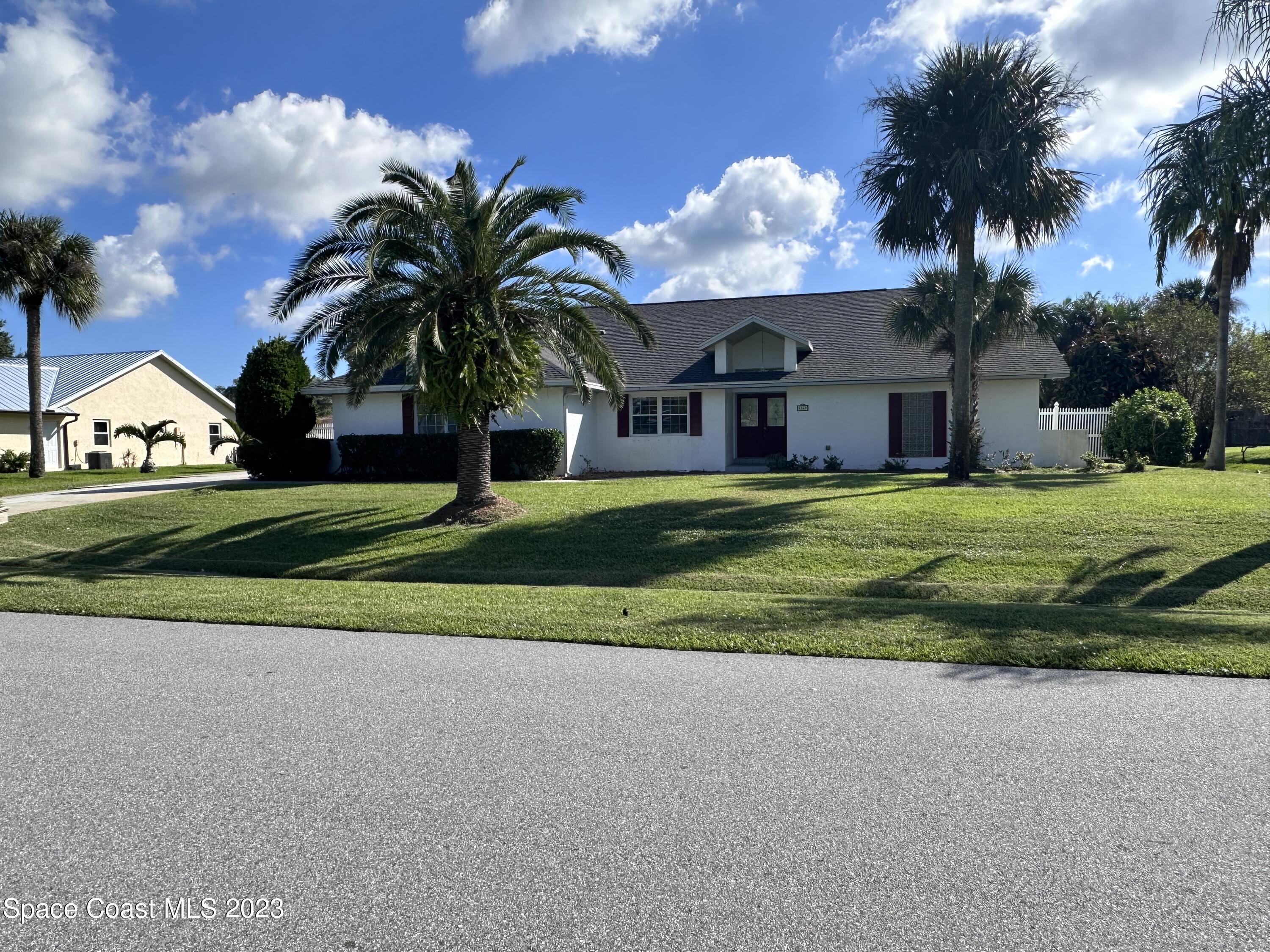 1369 Elcon Drive Melbourne, FL 32904 - Photo 2 of 13 a view of a house with a big yard and palm trees