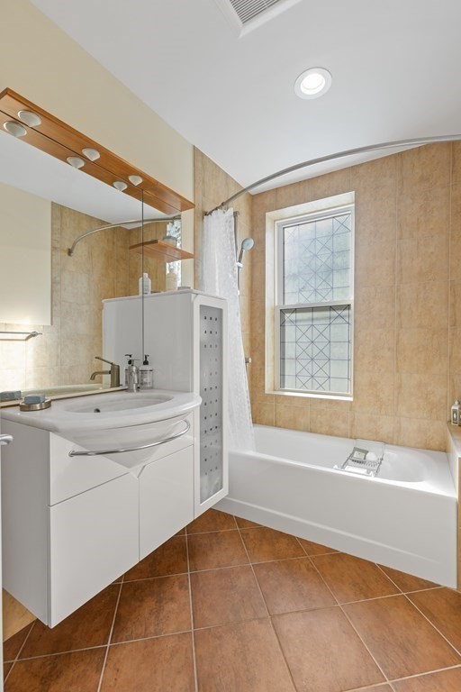20 Strathmore Road, Unit 2 Brookline, MA 02445 - Photo 12 of 28 a bathroom with a granite countertop sink a mirror and a bathtub