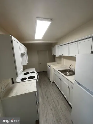 a kitchen with sink a stove and white cabinets