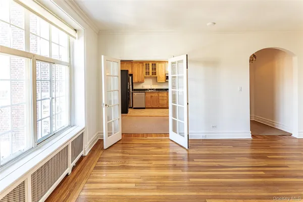 a view of an empty room with wooden floor and a window