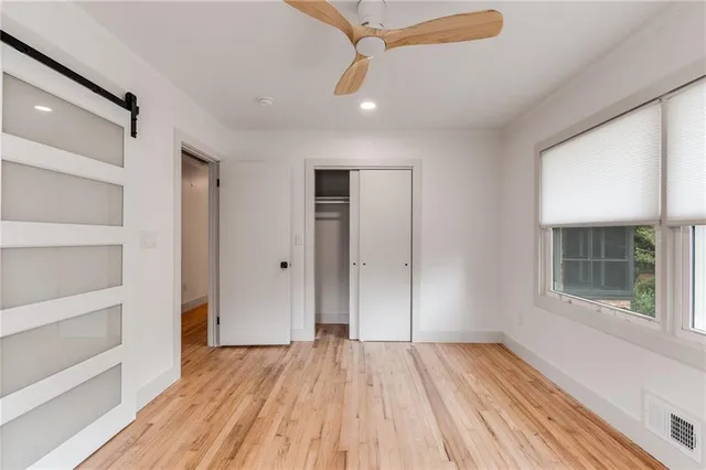 a view of empty room with wooden floor and fan