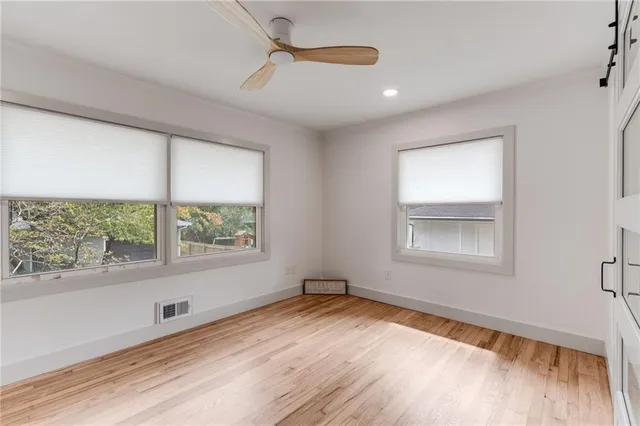 a view of empty room with wooden floor and fan