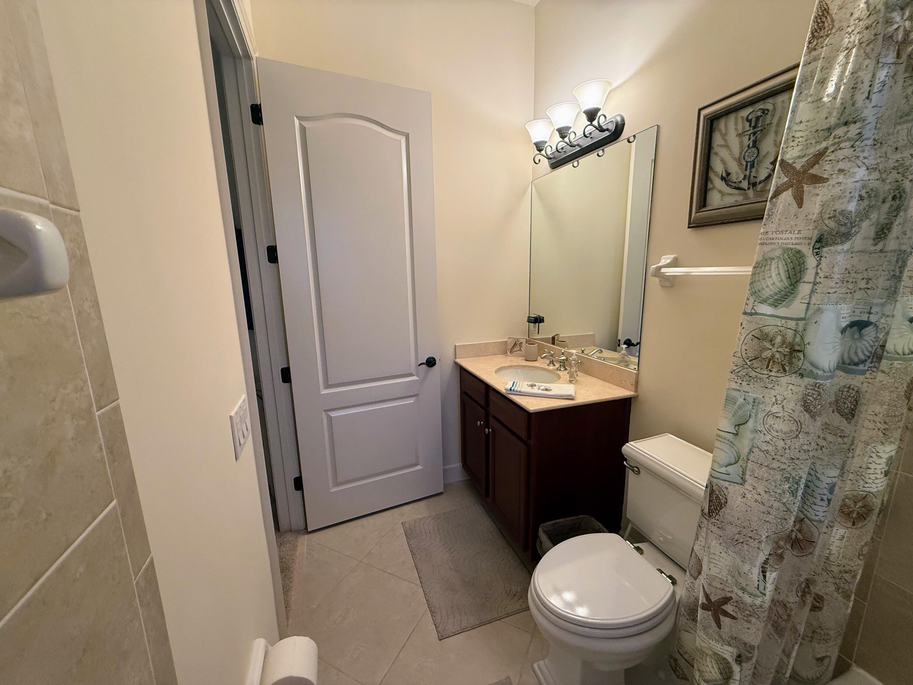 20 Orange Avenue, Unit 9 Fort Pierce, FL 34950 - Photo 50 of 92 a bathroom with a sink a toilet a mirror a vanity and shower