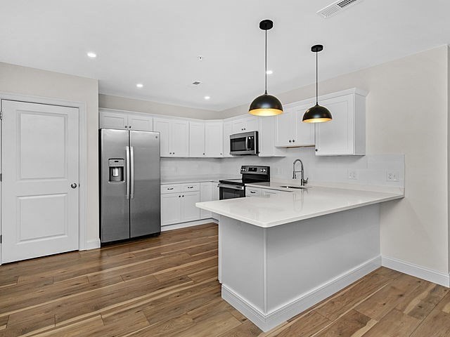 1 Pleasant Street, Unit 306 Cohasset, MA 02025 - Photo 4 of 23 a kitchen with stainless steel appliances granite countertop a sink a stove a refrigerator and island with wooden floor