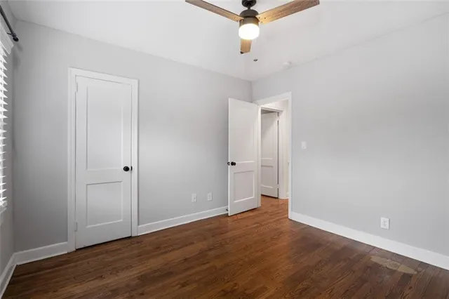an empty room with wooden floor and a ceiling fan