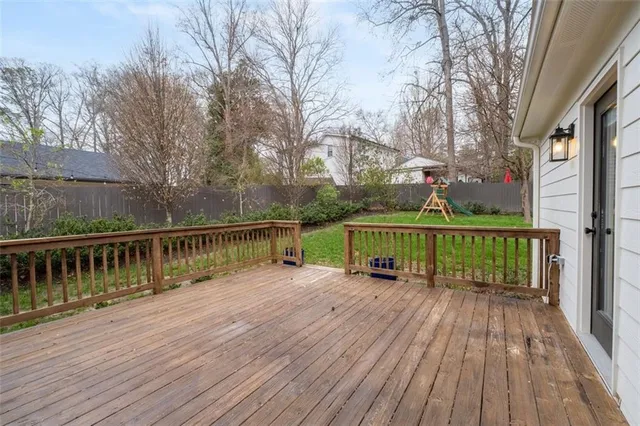 a view of a deck with wooden floor and fence with a large garden