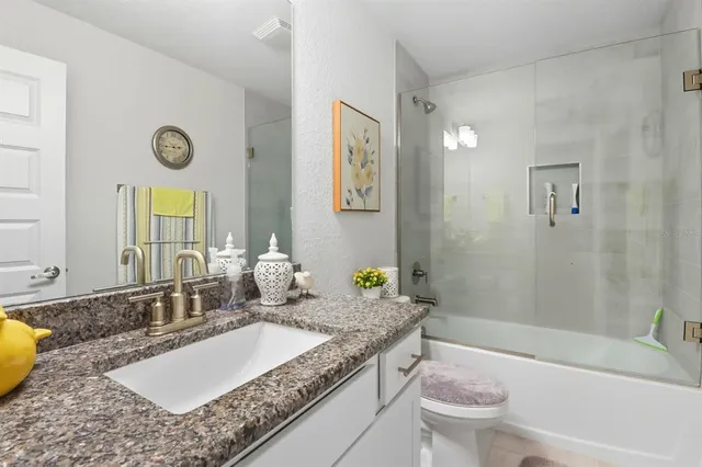 a bathroom with a granite countertop tub sink and mirror