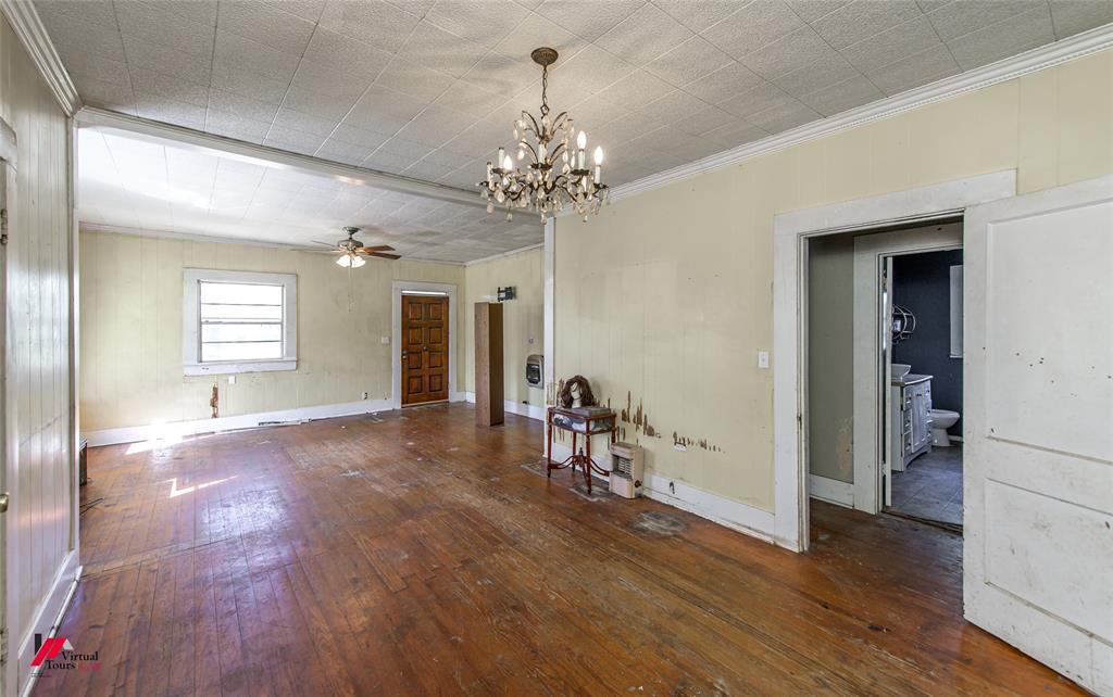 179 Daniel Thomas Road Springhill, LA 71075 - Photo 2 of 37 Unfurnished room with wood-type flooring, ornamental molding, ceiling fan with notable chandelier, baseboards, and heating unit