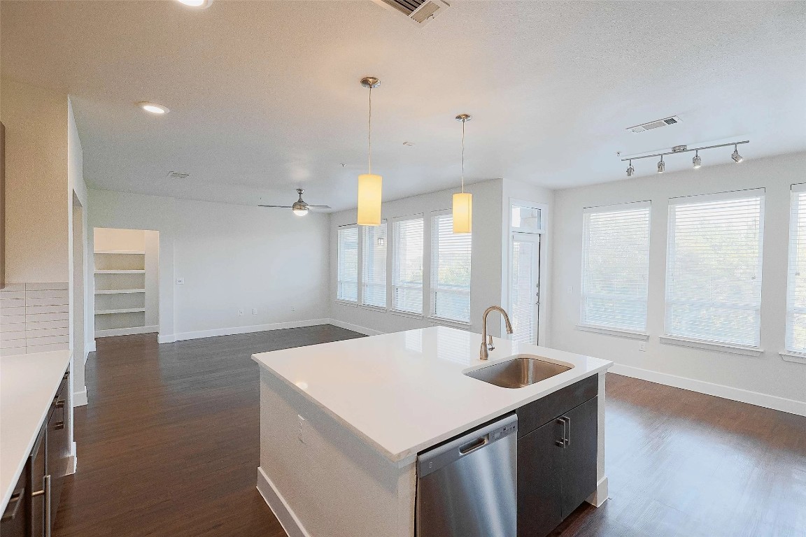 4800 Steiner Ranch Boulevard, Unit 20002 Austin, TX 78732 - Photo 29 of 29 Kitchen featuring decorative light fixtures, open floor plan, stainless steel dishwasher, dark wood-style floors, and a center island with sink
