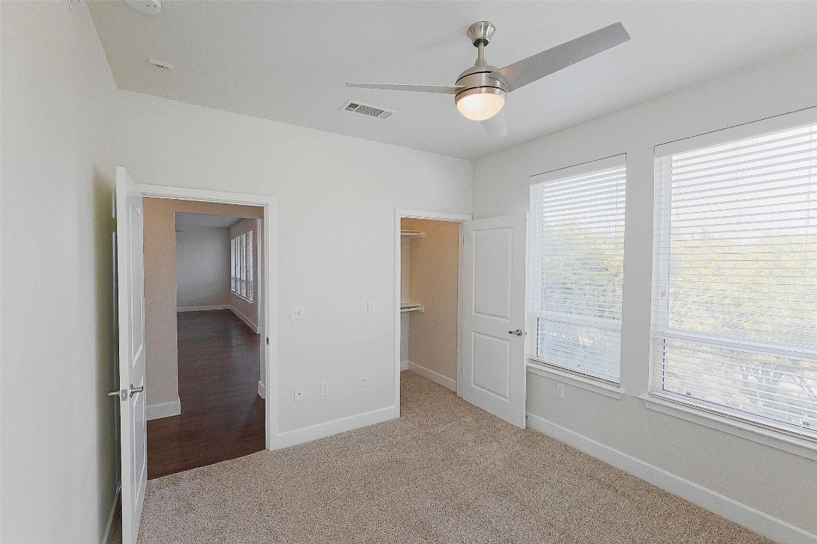 4800 Steiner Ranch Boulevard, Unit 20002 Austin, TX 78732 - Photo 16 of 29 Unfurnished bedroom featuring a walk in closet, light colored carpet, and a ceiling fan