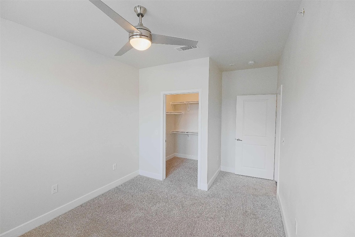 4800 Steiner Ranch Boulevard, Unit 20002 Austin, TX 78732 - Photo 19 of 29 Unfurnished bedroom featuring a walk in closet, light carpet, and ceiling fan