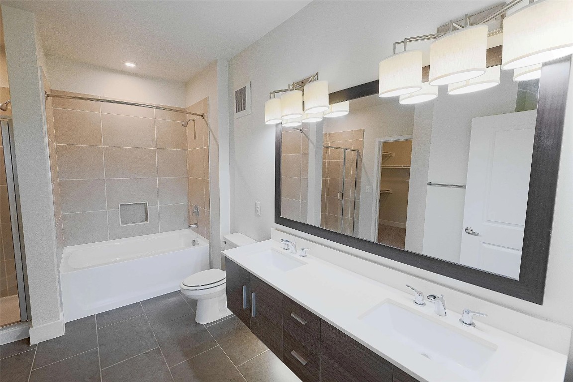 4800 Steiner Ranch Boulevard, Unit 20002 Austin, TX 78732 - Photo 23 of 29 Full bath with double vanity, a spacious closet, a stall shower, dark tile patterned flooring, and a bathtub