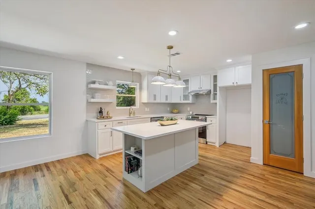 a kitchen with kitchen island stainless steel appliances a stove and wooden floor