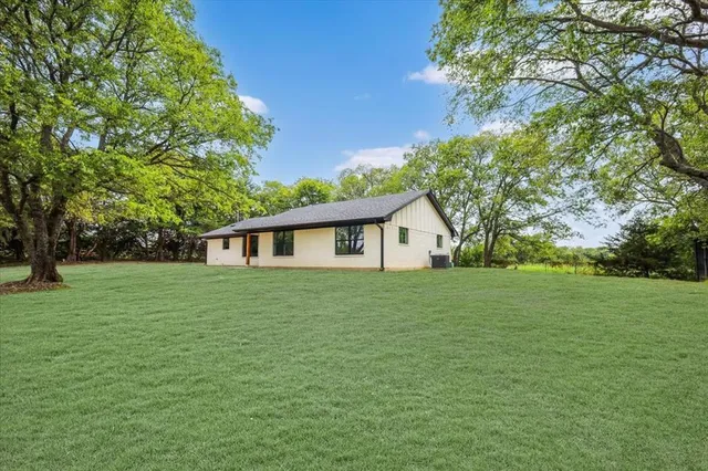 a view of a yard in front of a house with large trees
