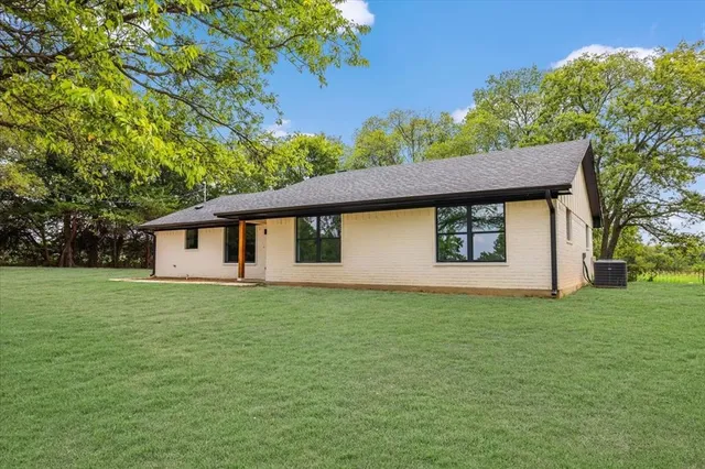 a house that is sitting in the grass with large trees
