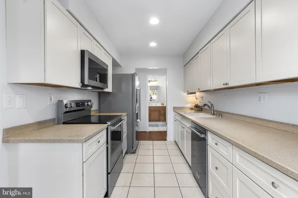 a kitchen with stainless steel appliances granite countertop a sink a stove top oven and white cabinets