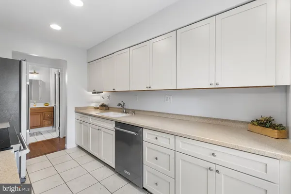 a kitchen with granite countertop white cabinets and stainless steel appliances