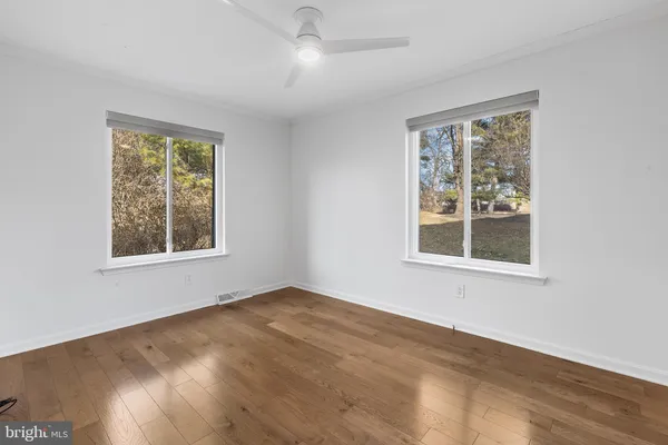 a view of an empty room with a window and wooden floor