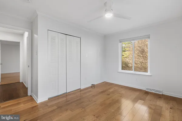 a view of empty room with wooden floor and fan