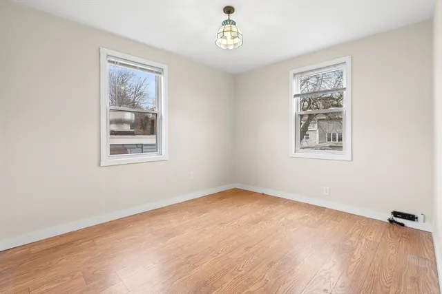 a view of an empty room with a window and wooden floor
