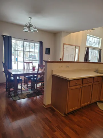 a open kitchen with stainless steel appliances granite countertop a stove top oven a dining table and chairs with wooden floor