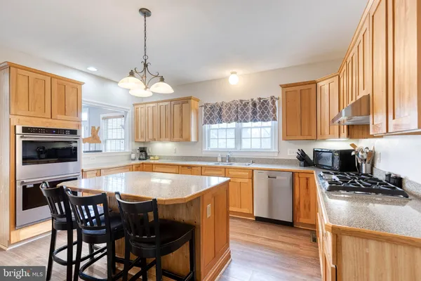 a kitchen with stainless steel appliances granite countertop a stove a sink a microwave a center island and a window