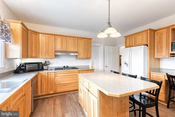 a kitchen with stainless steel appliances granite countertop wooden cabinets a stove a sink a dining table and chairs