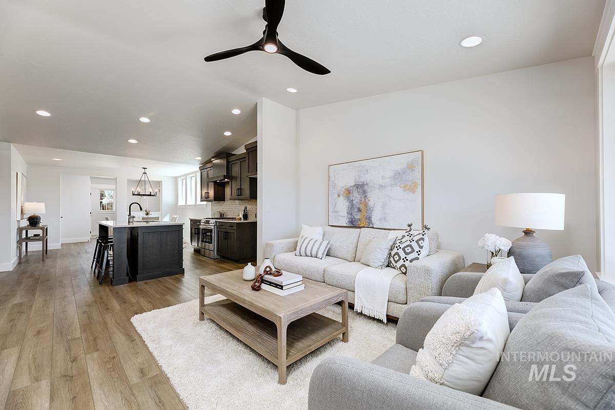 7151 South Skybreak Lane Meridian, ID 83642 - Photo 10 of 26 Open-concept living space featuring wood-finish flooring, recessed lighting, and a dark-toned kitchen island with bar seating