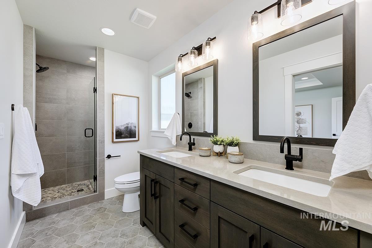 7151 South Skybreak Lane Meridian, ID 83642 - Photo 12 of 26 Spacious bathroom featuring a dual vanity with light-toned countertops, dark wood-finish cabinetry, and black fixtures
