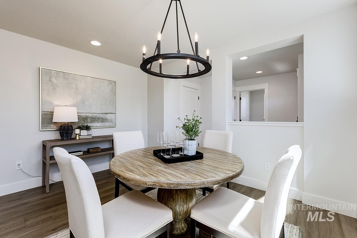 7151 South Skybreak Lane Meridian, ID 83642 - Photo 3 of 26 Dining area featuring a circular wood-finish table, a black metal chandelier, wood-finish flooring, recessed lighting, and a pass-through opening to an adjacent space