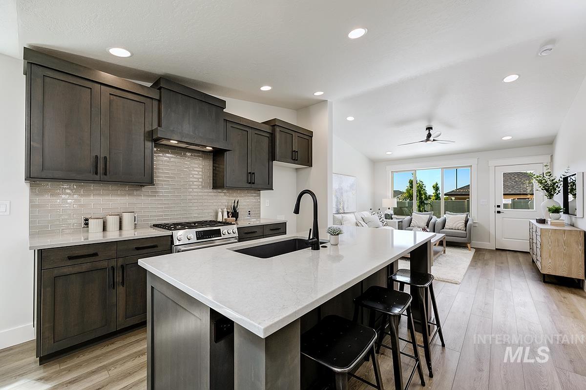7151 South Skybreak Lane Meridian, ID 83642 - Photo 8 of 26 Kitchen island with a built-in sink, quartz countertop, and seating for three