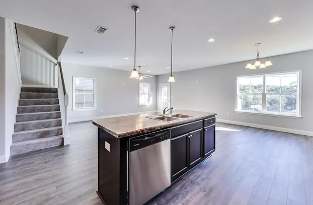 a kitchen with stainless steel appliances granite countertop a stove a sink a window and wooden floor
