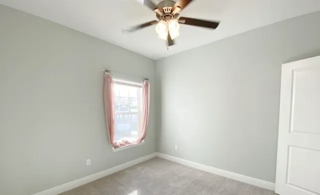 an empty room with a window and a fan