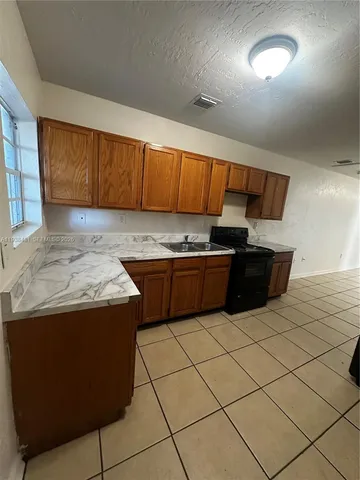a kitchen with granite countertop a sink a counter space and cabinets