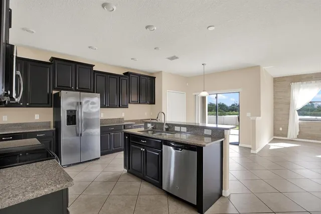 a kitchen with stainless steel appliances granite countertop a stove a sink dishwasher a refrigerator and a microwave