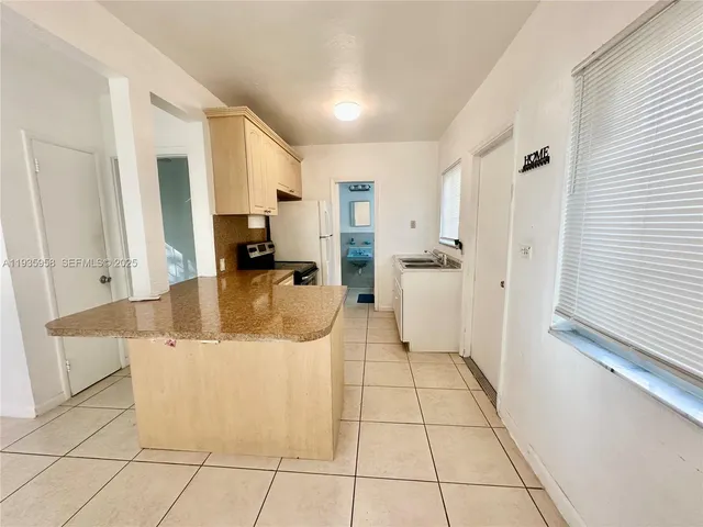 a kitchen with stainless steel appliances kitchen island granite countertop a refrigerator and a sink
