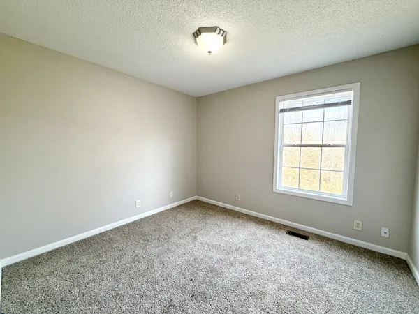 a view of an empty room and window and ceiling fan