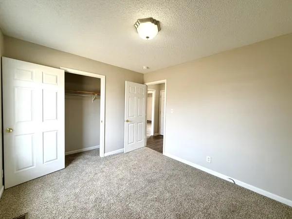 an empty room with a chandelier fan and windows