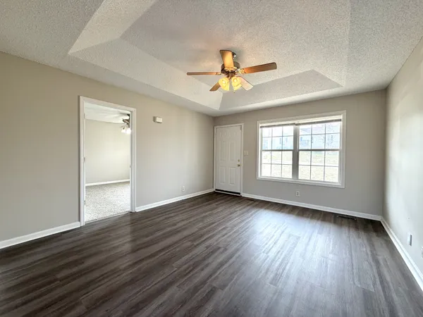 a view of an empty room with window and wooden floor
