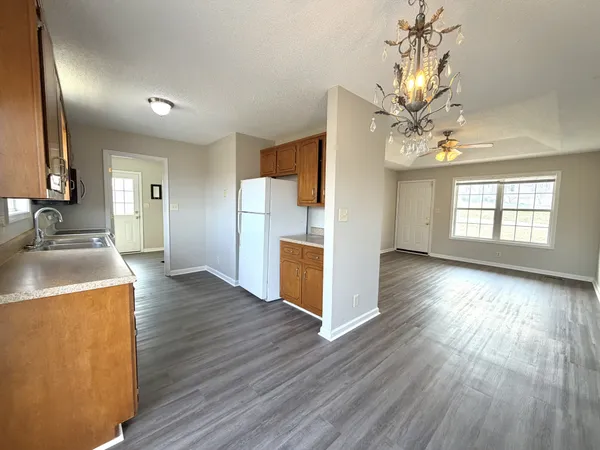 a kitchen with stainless steel appliances granite countertop a refrigerator a sink dishwasher a stove with wooden cabinets and floors