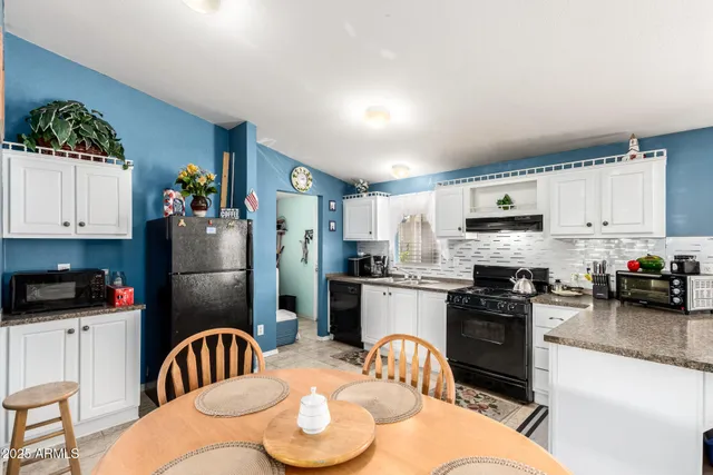 a kitchen with stainless steel appliances kitchen island granite countertop a refrigerator a stove a sink a dining table and chairs with wooden floor