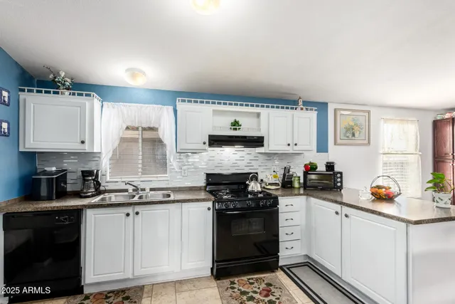 a kitchen with stainless steel appliances a stove a sink and white cabinets