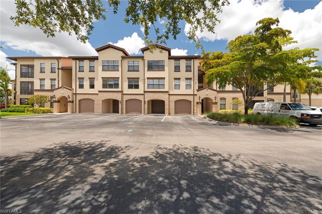 12980 Positano Circle, Unit 308 Naples, FL 34105 - Photo 2 of 22 a front view of a building with large trees